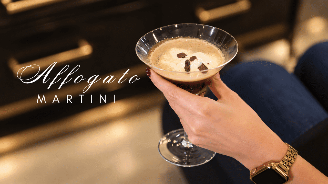 A hand holds an affogato martini topped with whipped cream and chocolate shavings.