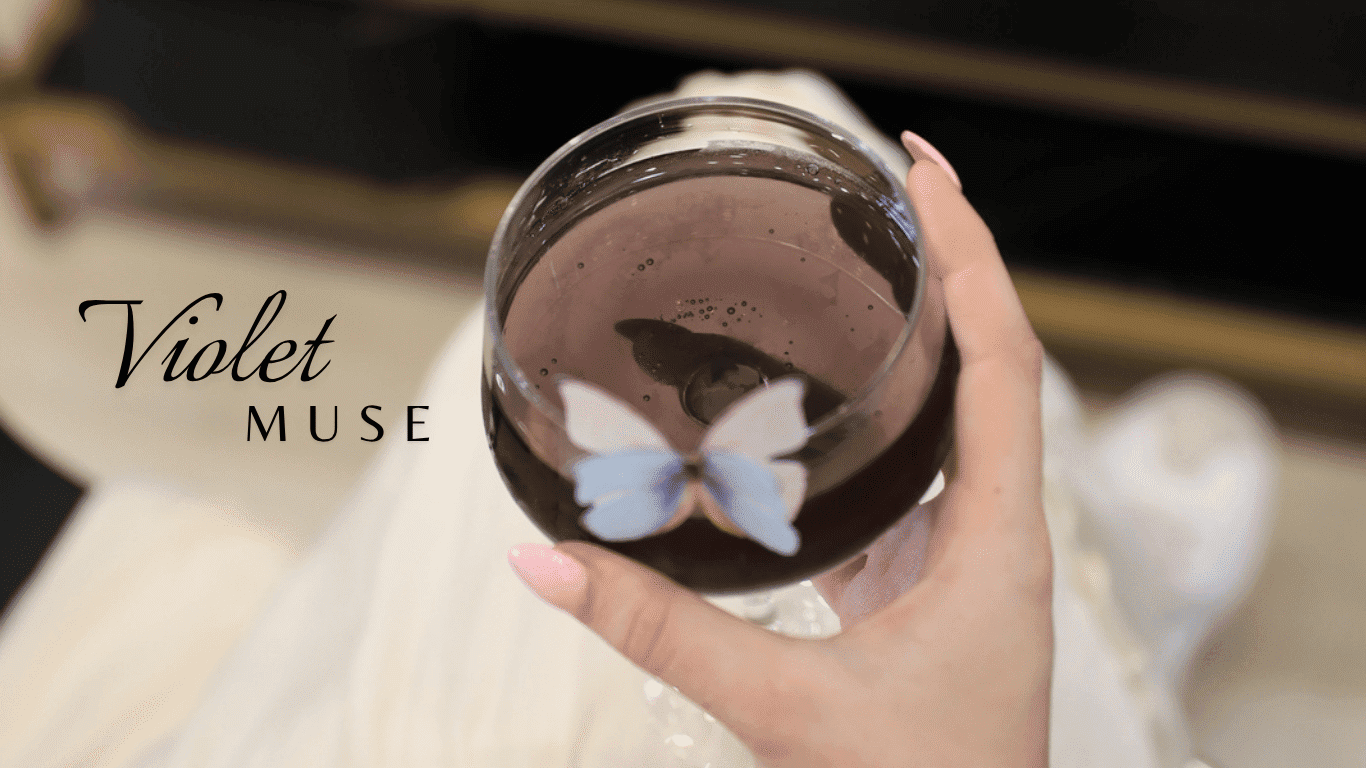 A person holding a glass of purple drink with a butterfly on it, text: "Violet Muse".